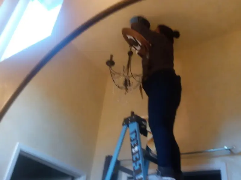Electrician installing a chandelier in a Crouch Mesa residence